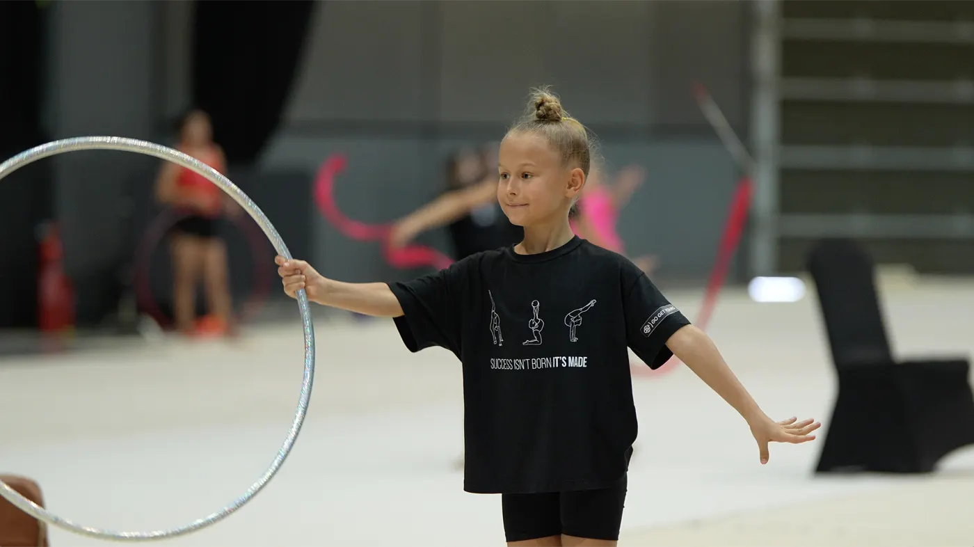 A gymnast holding a hoop and working on her position